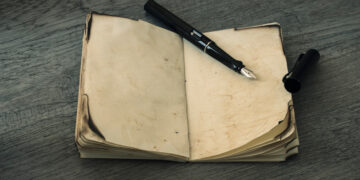 Stara, zniszczona księga na drewnianym stole, symbolizująca bogatą historię Boguszowa-Gorc.