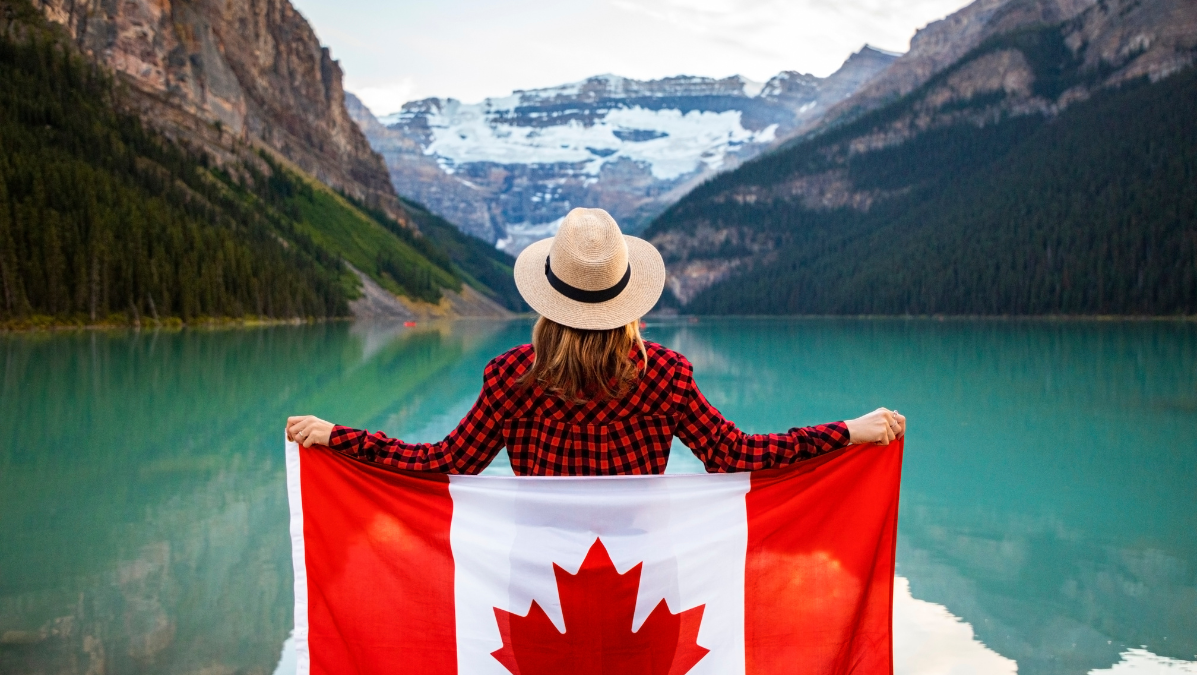 Kobieta trzymająca flagę Kanady na tle gór i jeziora